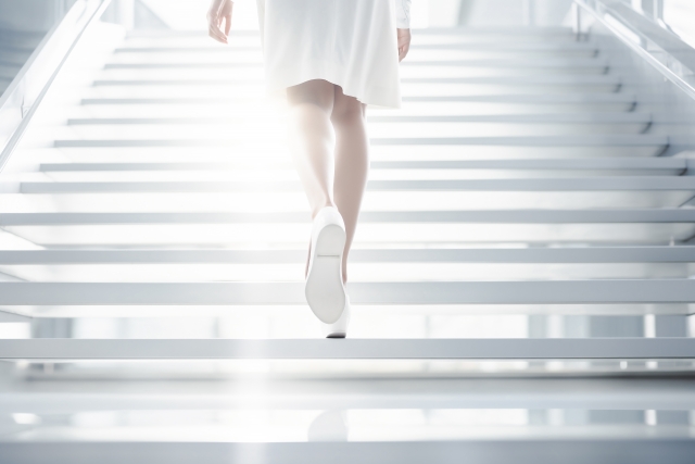 光に向かって階段を上る女性